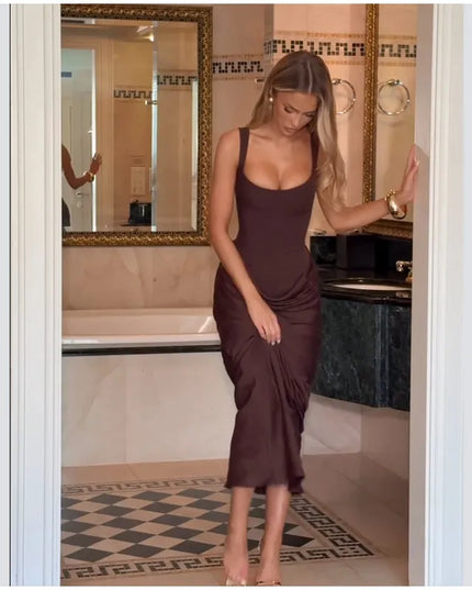 Model wearing a brown pleated maxi dress in a stylish bathroom setting.
