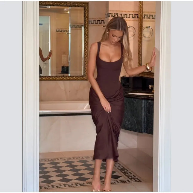 Model wearing a brown pleated maxi dress in a stylish bathroom setting.