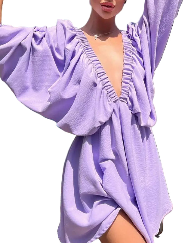 Model wearing a lavender deep V-neck pleated dress with long sleeves by a poolside.