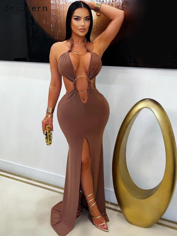 Woman in a brown dress with cut-out design standing indoors.
