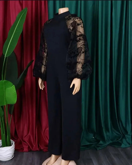 Mannequin wearing a black outfit with sheer sleeves against a red and green curtain background.