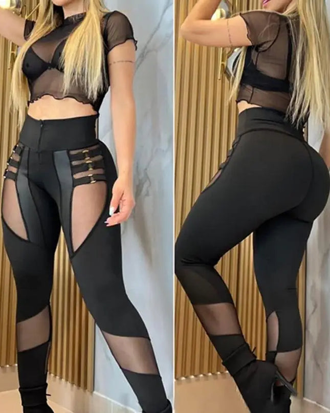 Black outfit with sheer panels worn by a person, against a marble wall.
