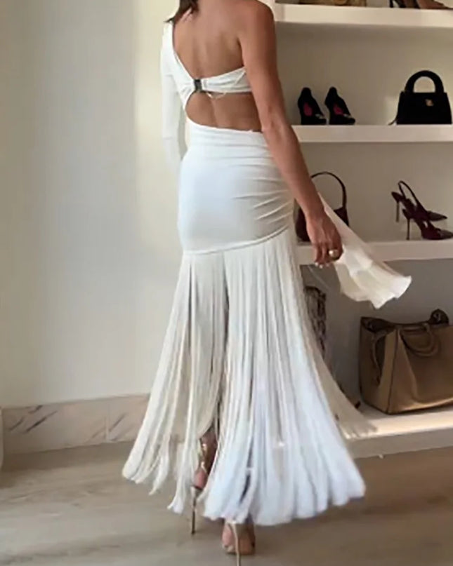 Woman wearing a white fringe dress in a room with shelves and bags.