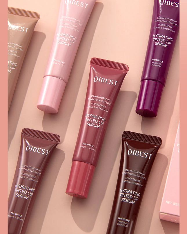 Qibest hydrating tinted lip serums in various colors on a pink background