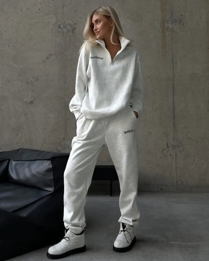 Person wearing a white tracksuit with 'Quiksilver' branding in a minimalistic setting.