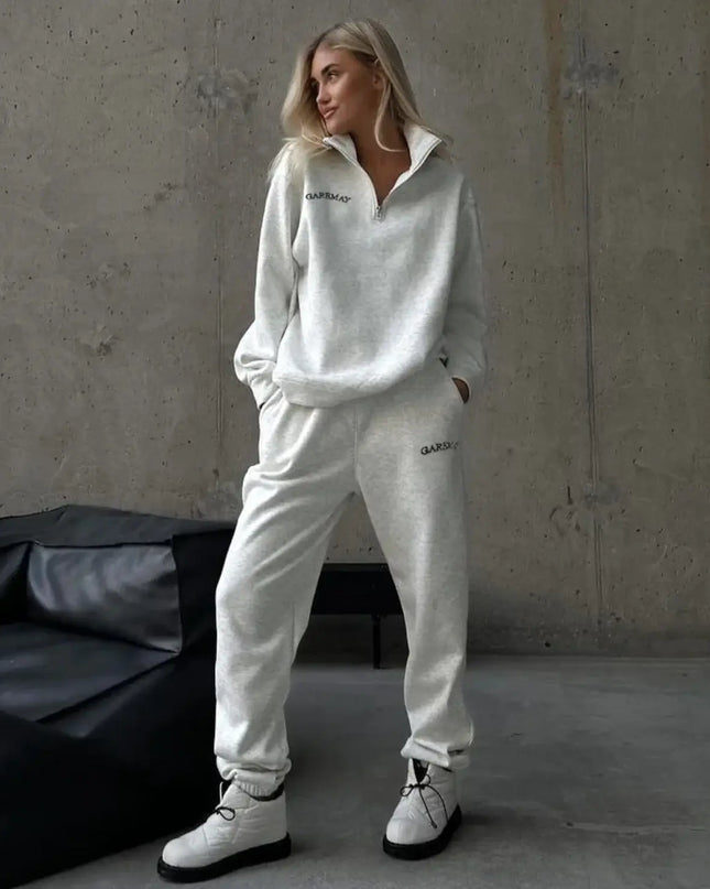 Person wearing a white tracksuit with 'Quiksilver' branding in a minimalistic setting.