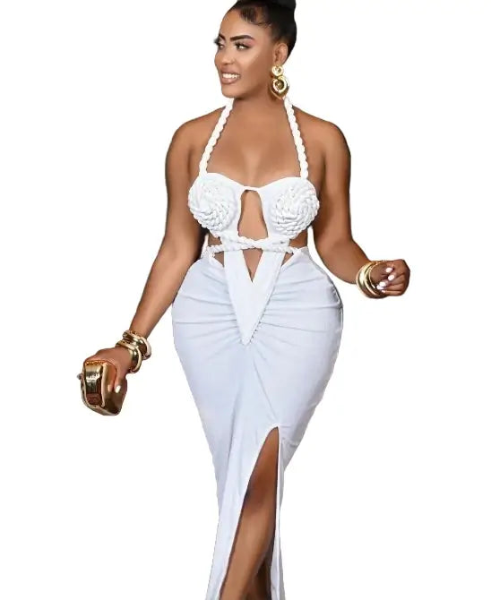 Woman in a white dress with a high slit standing in an indoor setting.