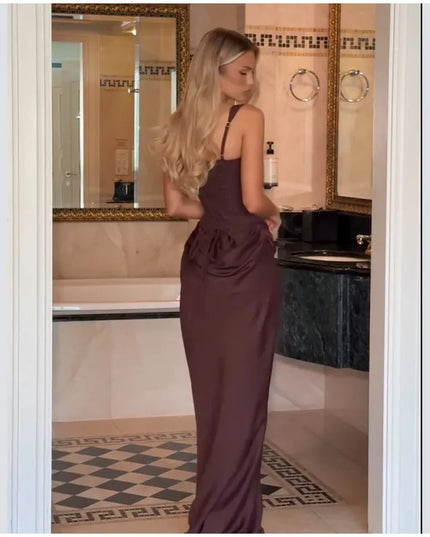 Model showcasing a brown pleated maxi dress from the back in a stylish bathroom setting.