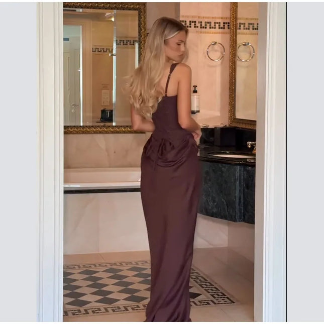 Model showcasing a brown pleated maxi dress from the back in a stylish bathroom setting.