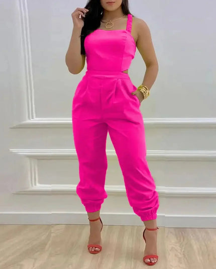 Woman wearing a bright pink jumpsuit against a white wall.