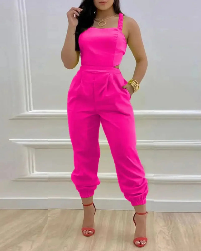 Woman wearing a bright pink jumpsuit against a white wall.