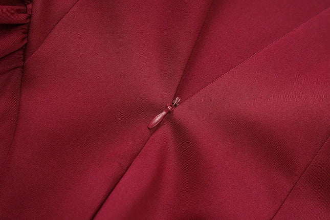 Close-up of the elegant fabric and zipper detail of an off shoulder mini dress party outfit in deep burgundy color.