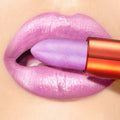 Purple lipstick being applied to a lip with a beige background