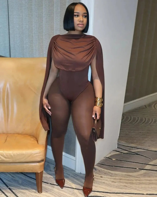 Woman in a brown outfit with a cape standing in a room with a beige couch.