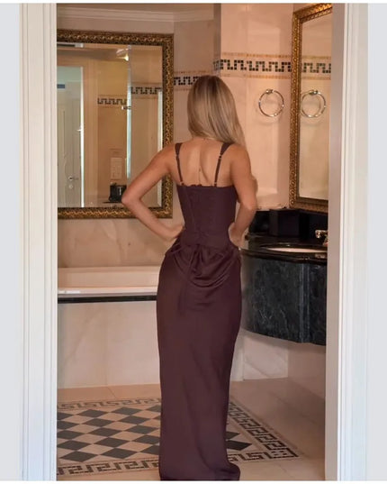 Brown pleated maxi dress worn by a woman from the back, showcasing its elegant design in a stylish bathroom setting.