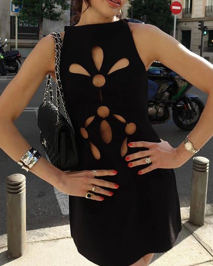 Woman wearing a black dress with cut-out design on a city street.