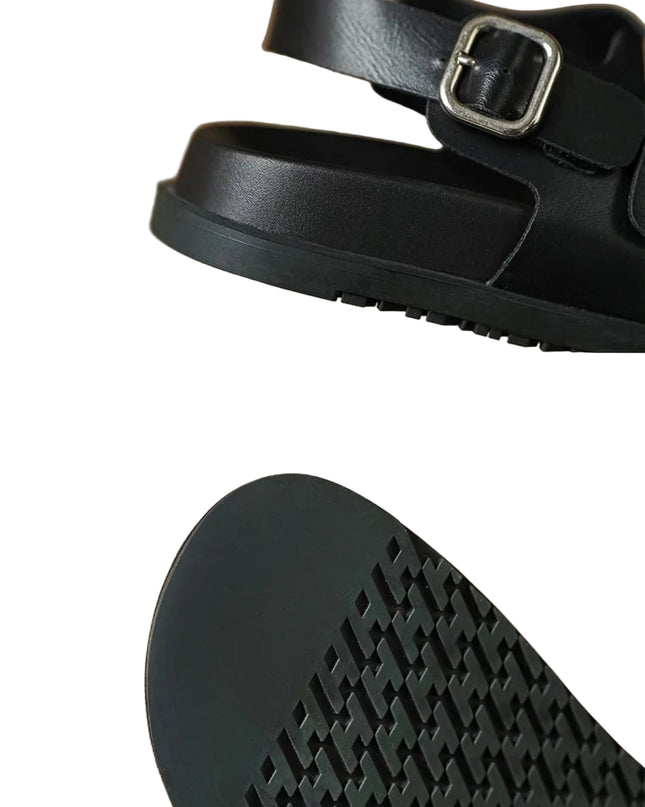 Black sandal with a buckle on a beige background