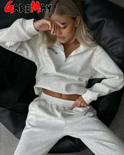 Person wearing a white 'Garmay' tracksuit sitting on a black chair.