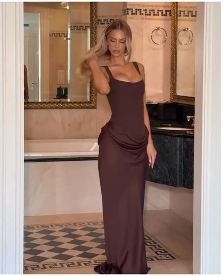 Model wearing a brown pleated maxi dress in a stylish bathroom setting, showcasing its elegant silhouette.