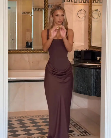 Model showcasing a brown pleated maxi dress in a stylish bathroom setting, emphasizing elegance and sophistication.