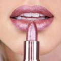 Close-up of a person applying pink lipstick with a matching lipstick visible.