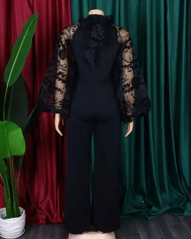 Mannequin wearing a black outfit with sheer sleeves against a green and red curtain background.