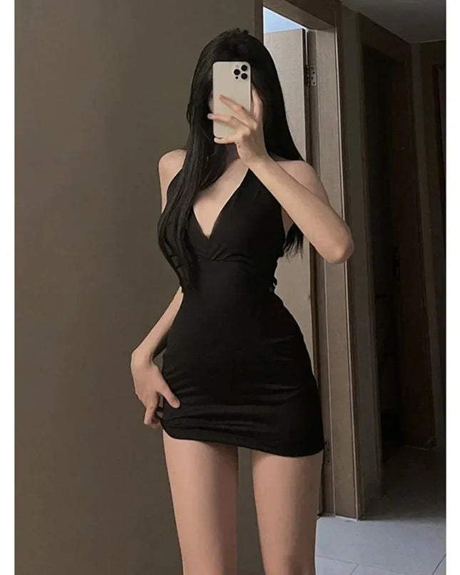 Person wearing a black dress taking a mirror selfie.
