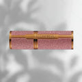 Pink glittery lipstick with gold accents on a light gray background