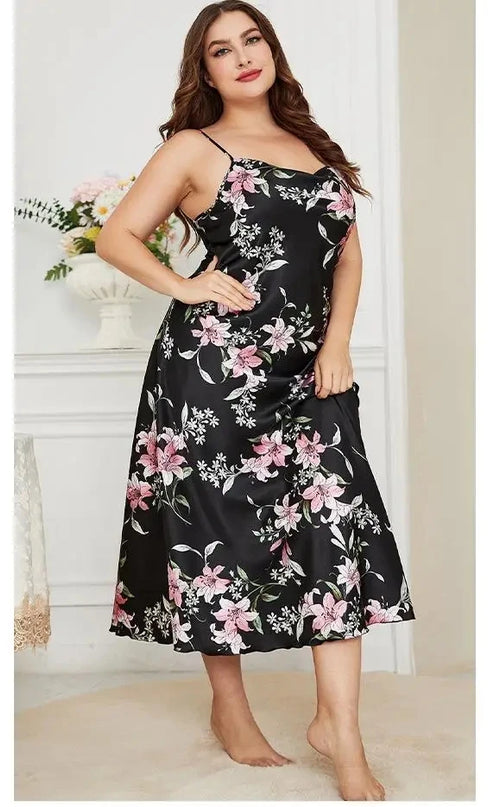 Woman wearing a black floral dress in a room with white walls and a vase of flowers.