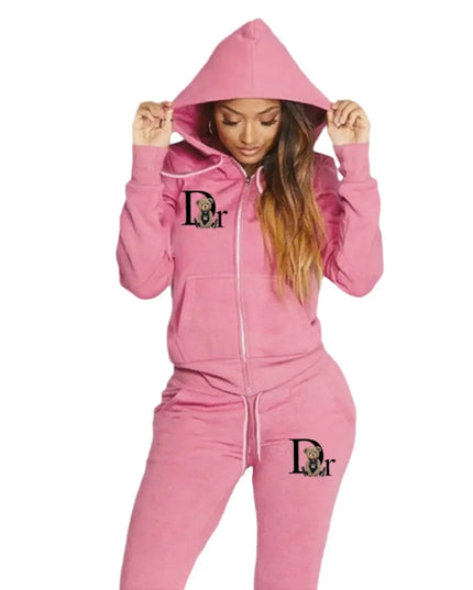 Person wearing a pink hoodie and matching pants with a logo on a gray background
