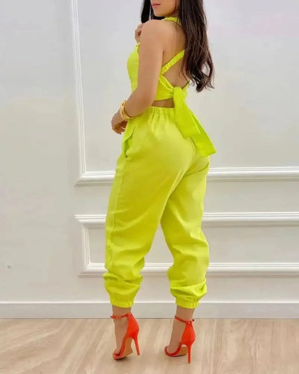 Person wearing a bright yellow outfit with orange heels against a white wall.