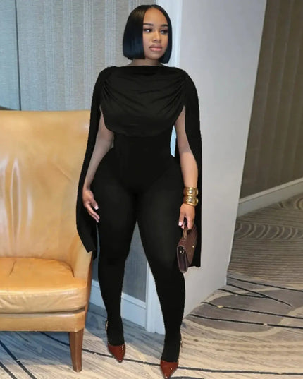 Woman in a black outfit standing in an indoor setting with a beige chair and carpeted floor.