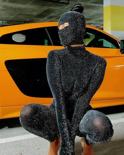 Person wearing a black glittery outfit sitting in front of an orange car.
