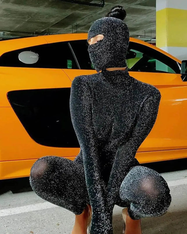 Person wearing a black glittery outfit sitting in front of an orange car.