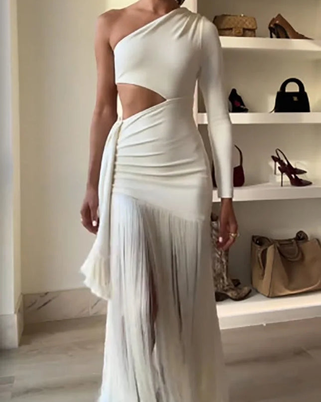 Woman wearing a white one-shoulder dress with cut-out design in a room with shelves displaying bags.