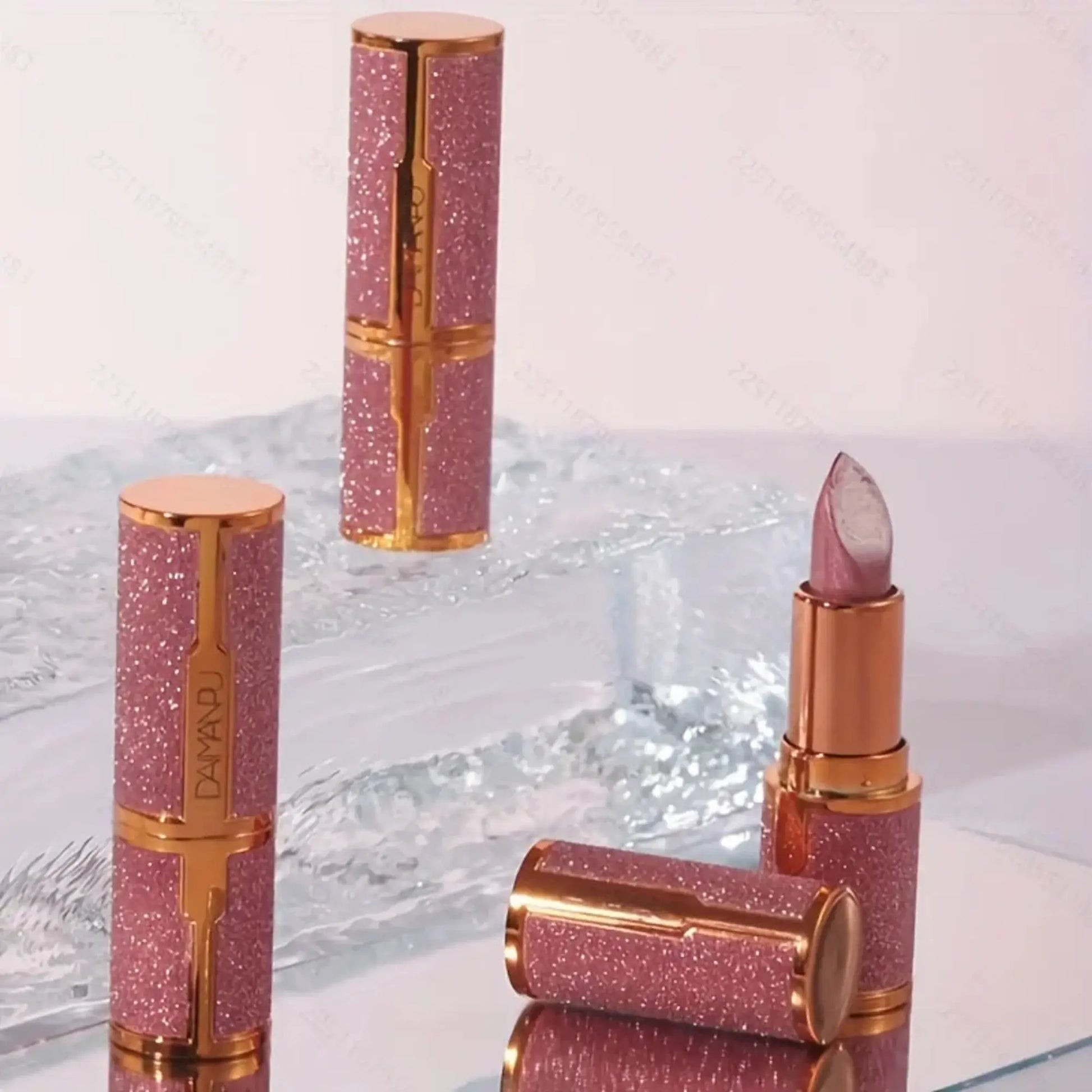 Pink glittery lipsticks with gold accents on a reflective surface