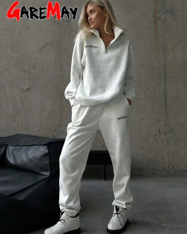 Person wearing a white tracksuit with 'GAREMAY' branding against a gray wall.