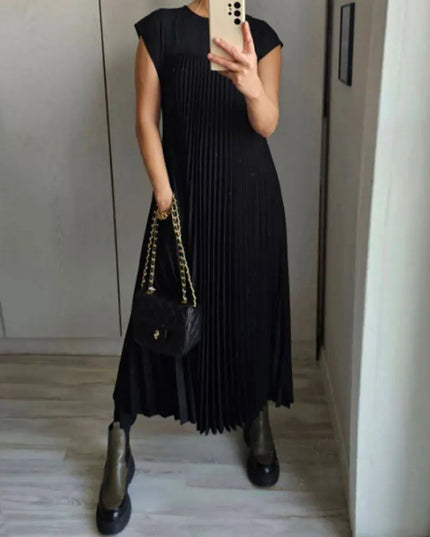 Women’s elegant sleeveless dress with pockets in black, pleated design and stylish handbag.