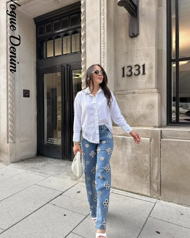 Woman in white shirt and blue patterned pants walking in front of a building with 'Vogue Denim' branding.