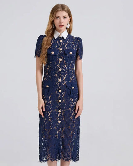 Woman wearing a navy lace dress with gold buttons on a light gray background