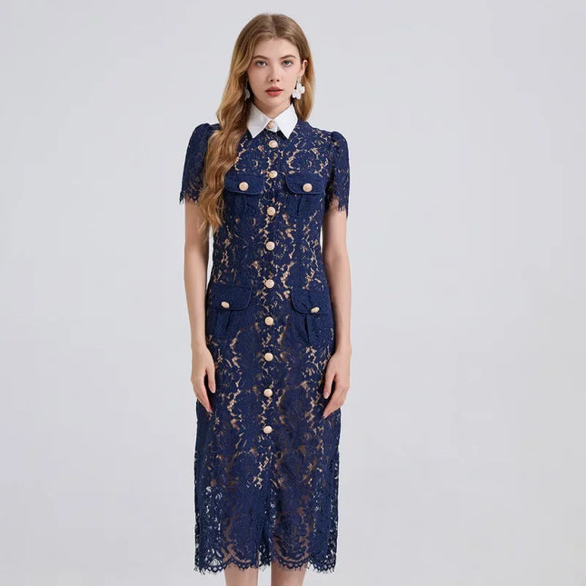 Woman wearing a navy lace dress with gold buttons on a light gray background
