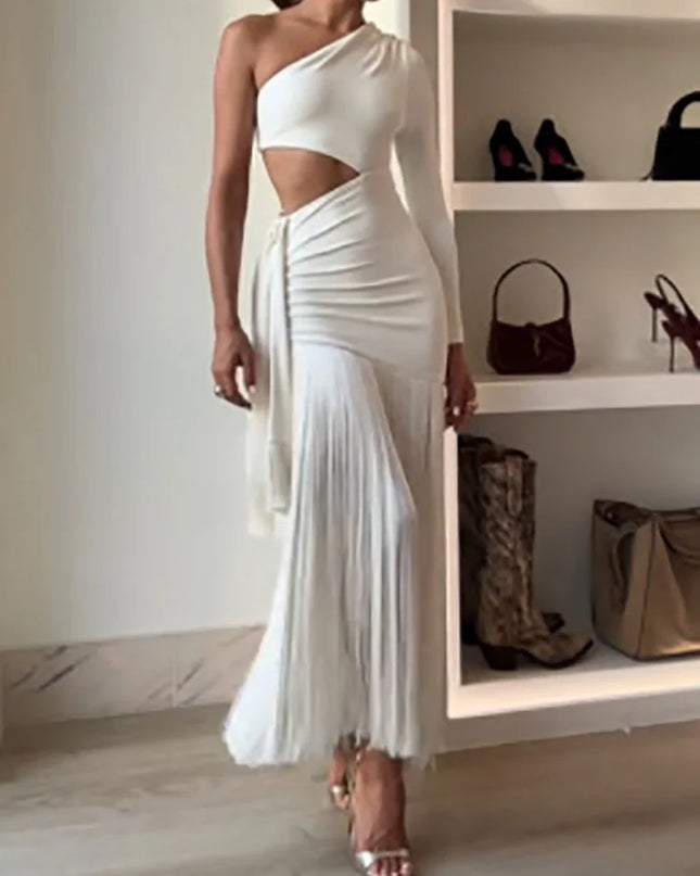 Woman wearing a white one-shoulder dress with cut-out design, standing in front of a shelf with bags.