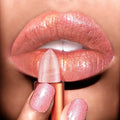 Close-up of a hand holding a pink lipstick against a blurred background