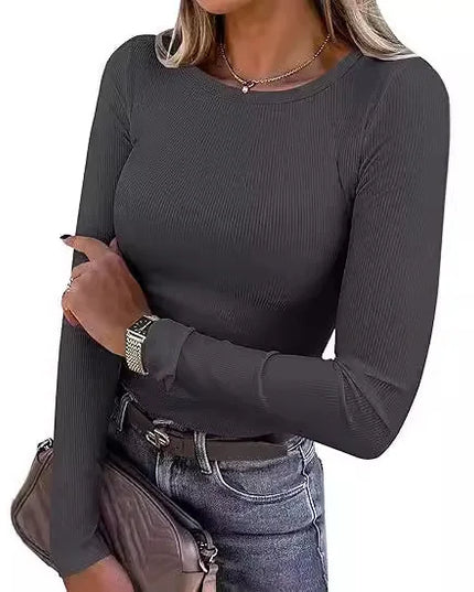 Woman wearing a dark gray long-sleeve top and jeans on a white background