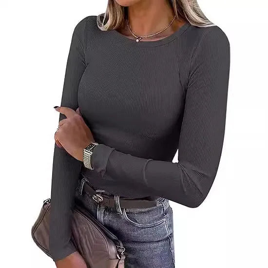Woman wearing a dark gray long-sleeve top and jeans on a white background