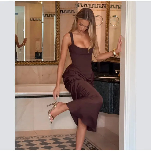 Model showcasing a brown pleated maxi dress in a luxurious bathroom setting.