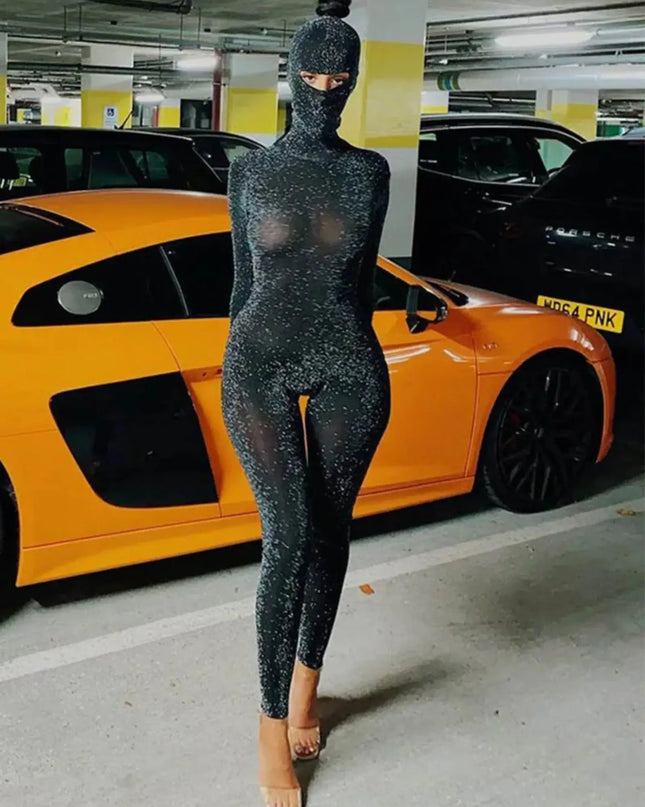 Person wearing a black bodysuit with a hood in a parking garage with cars and yellow walls.