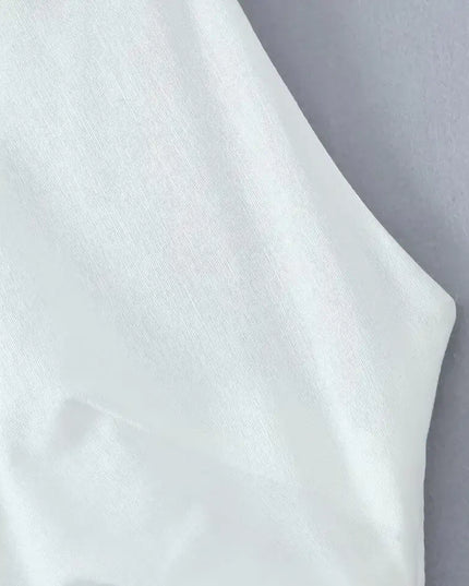 Close-up of the fabric and collar of a white cotton linen summer dress featuring a backless design.