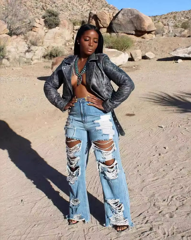 Woman in a leather jacket and ripped jeans standing in a desert landscape