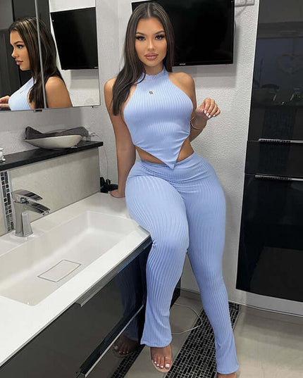 Woman in a blue ribbed outfit posing in a bathroom.